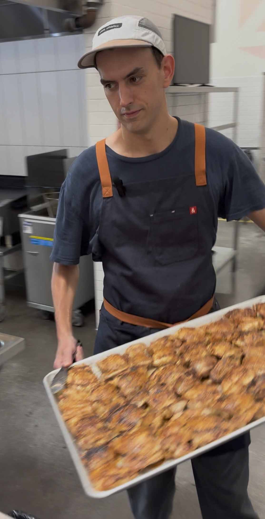 Ben carrying a tray of freshly cooked chicken in the kitchen