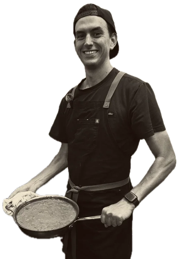 Ben, the chef, in his kitchen holding a pan of butter chicken