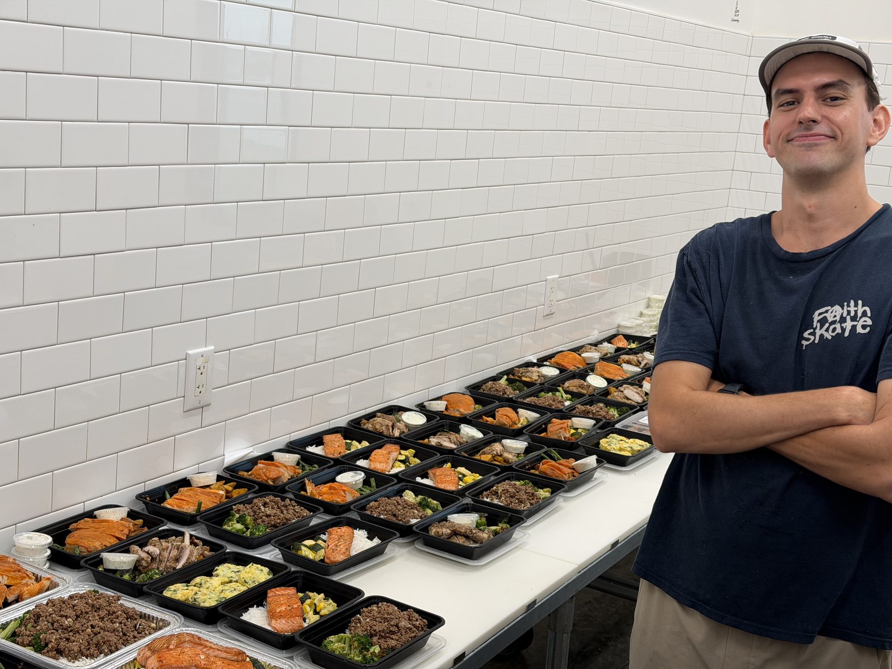 Ben next to a table of Full Time Food meals packed and ready for Sunday delivery